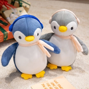 Detail of plush penguin toys with cozy scarves and earmuffs on a soft rug