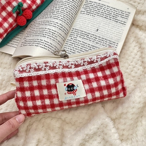 Close-up of red and white checkered plush pencil case with lace trim and cat patch