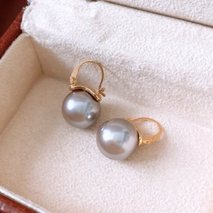 Détail de boucles d'oreilles créoles avec perles de verre grises dans un écrin en velours