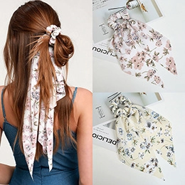 Detailed view of large floral bow hair scrunchies with long ribbons in pink and blue patterns
