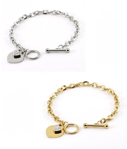 Détail macro du fermoir OT et des pendentifs cœur sur des bracelets en or et argent poli
