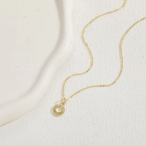 Detailed close-up of a golden smiley face pendant necklace on a clean white surface
