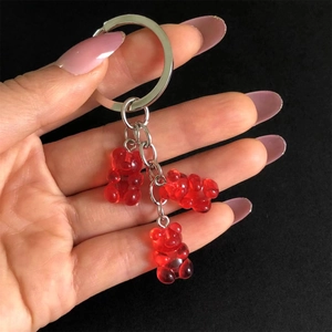 Detail of red jelly gummy bear charms on a silver metal keychain over a black background