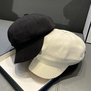 Detailed texture of retro checkered newsboy caps in black and cream on white tray