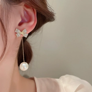 Dettaglio di orecchini a fiocco con perle e cristalli indossati da una modella