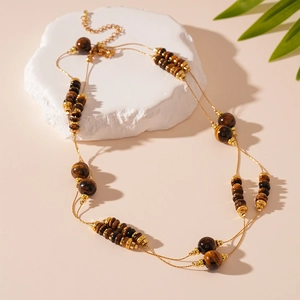 Detail of double-layer tiger eye stone necklace with gold beads on white stone