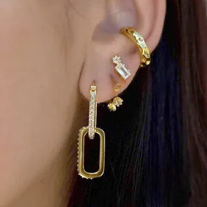 Macro shot of gold ear cuff and rectangle drop earrings with zircon insets and textures