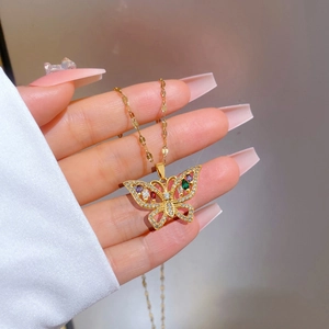 Detail of gold butterfly necklace pendant with colorful gemstones held in hand