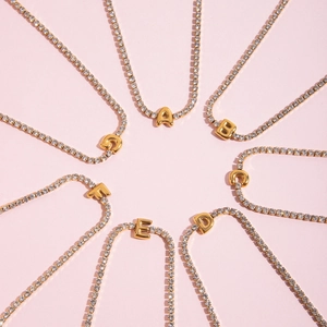 Detail of gold letter pendants A-G on a sparkling rhinestone tennis necklace set