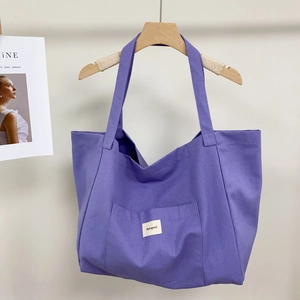 Close-up of purple canvas tote bag featuring reinforced stitching and exterior front pocket