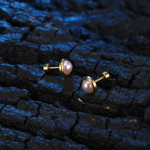 Minimalist vintage gold pearl stud earrings with screw back on dark wood background