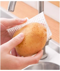 Spazzola flessibile bianca per verdure che pulisce una patata sopra il lavello