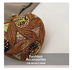 Detail of heart-shaped clutch featuring colorful sequins and intricate leaf embroidery