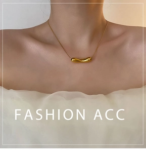 Close-up of golden fluid-style pod pendant on a snake chain worn with white fabric