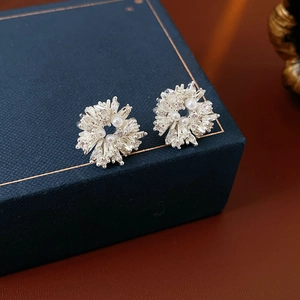 Détail des boucles d'oreilles fleur en argent avec zircons brillants et perles