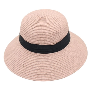 Detailed close-up of woven pink straw sun hat with black ribbon band on white background
