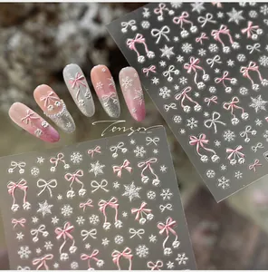 Close-up of 5D embossed nail stickers featuring pink bows and white winter snowflakes
