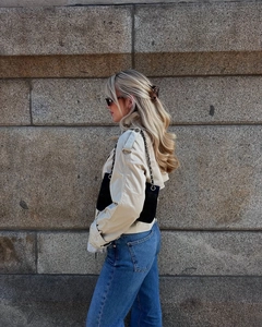 Detail of beige cropped trench coat with waist belt and black quilted chain shoulder bag