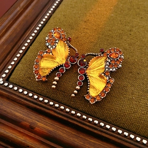 Detailed close-up of vintage butterfly brooches with amber rhinestones in a wooden frame