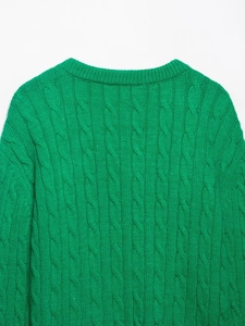 Close-up of vibrant green knitted sweater showing intricate eight-strand cable texture