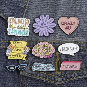 Flachbild von bunten Emaille-Pins mit motivierenden Sprüchen auf Denim-Hintergrund