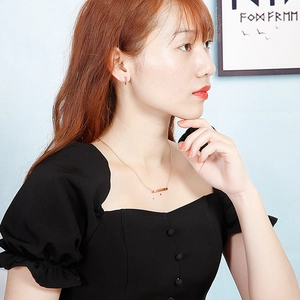 Elegant rose gold jewelry set with bar necklace and matching stud earrings on a model