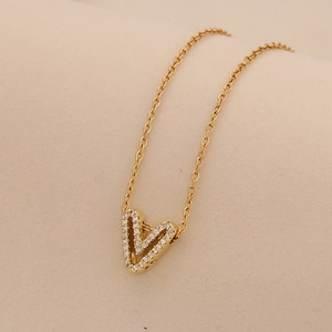 Close-up of golden V-letter pendant necklace with sparkling cubic zirconia inlay