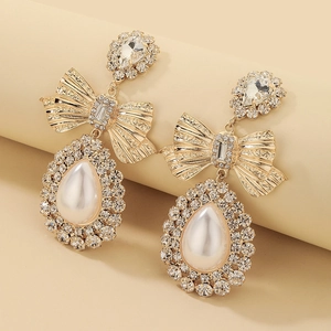 Macro detail of luxury bow earrings with teardrop pearls and pavé crystal setting