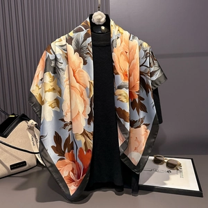 Detail of silk-satin square scarf with orange floral prints on a blue base and black borders