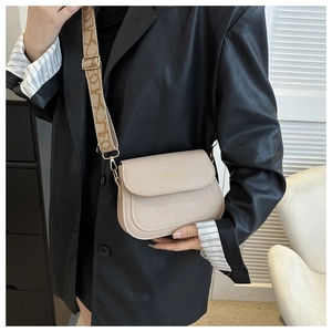 Beige crocodile texture saddle bag with patterned wide strap shown on a model