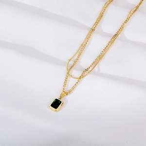 Détail d'un collier double épaisseur doré avec pendentif rectangulaire en zircon vert