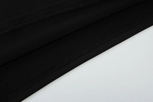 Détail de la double couture à l'ourlet et du tissu en maille noire de ce haut chic
