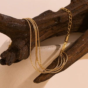 Detail of multi-layer 18K gold-plated stainless steel chain necklace on textured wood