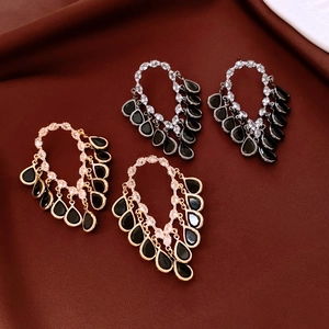 Detail of 18K gold plated drop tassel earrings with black stones and sparkling rhinestones