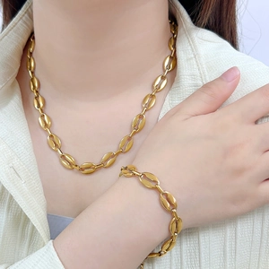 Elegant gold coffee bean link necklace and bracelet jewelry set worn by a female model