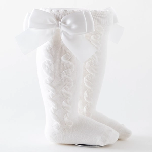 White cable knit baby high socks with large satin bows shown on a model leg
