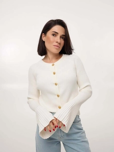 Detail of white knit cardigan showing embossed gold buttons and bell sleeve texture