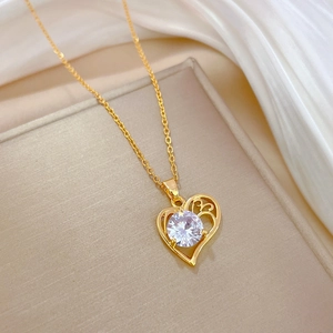 Macro shot of gold heart necklace with zircon on silk fabric, showing luxury details
