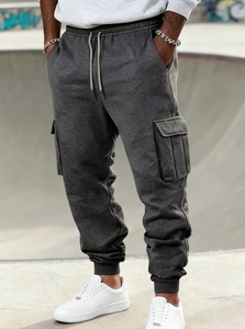 Detail of dark grey fleece cargo joggers showing drawstring waist and side flap pockets