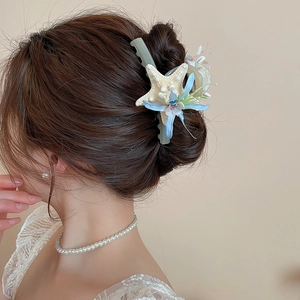 Detail of fabric flower and starfish hair clip with pearls on a model bun