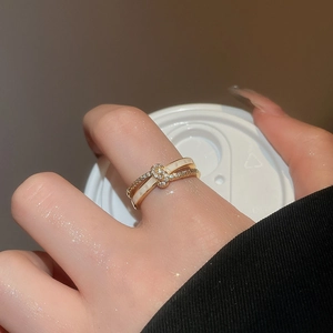 Detail of 18k gold plated double layer crossover ring with zircons and white enamel