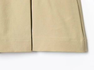 Dettaglio macro delle cuciture e dell'orlo in tessuto twill kaki sui pantaloni casual