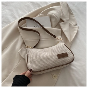 Close-up of beige woven canvas underarm bag with brown trim and leather label