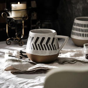 Minimalist ceramic mug with geometric pattern and unique triangular handle in a cozy setting
