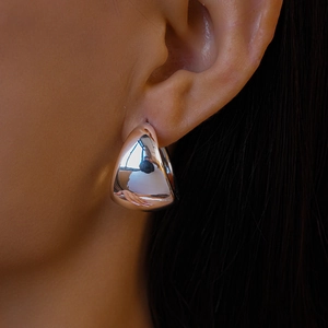 Close-up of chunky silver teardrop earrings on a model showing high-polish finish