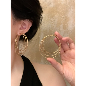 Close-up of gold multi-layered geometric hoop earrings with textured finish on model