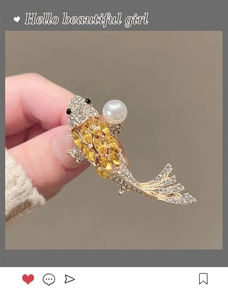 Macro shot of gold koi carp brooch with yellow crystals and a white pearl accent