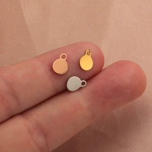 Polished stainless steel round pendant charms in gold, rose gold, and silver on fingers