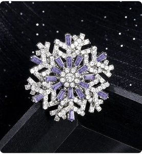 Macro detail of snowflake brooch with purple and white stones on a dark starry background