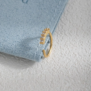 Detailed close-up of a gold leaf-shaped nose ring with five sparkling zircon stones